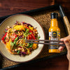 SIAM Peanut sauce bottle with a dish of noodles and vegetables on a wooden tray